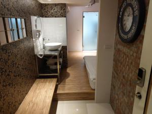 uma casa de banho com um lavatório e um relógio na parede em Cheers Loft Self Check-in Hotel em Taipei