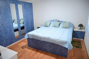 een slaapkamer met een blauw bed en een spiegel bij Oplenacki smestaj Milica in Topola