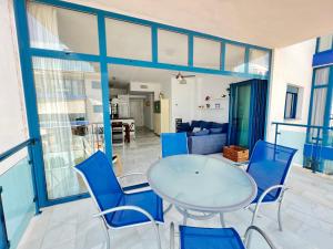 une salle à manger avec une table en verre et des chaises bleues dans l'établissement PUSHE Castell de Ferro Beach & Tradition 2, à Castell de Ferro