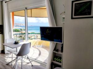a living room with a table and a television and a balcony at SOL & MAR Playa de las vistas Torres del Sol A504 in Arona