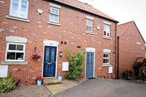 a red brick house with blue doors and windows at Cheerful two-bedroom townhouse near Leeds and York in Leeds