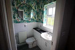 a bathroom with a sink and a toilet and a mirror at Stylish Village Townhouse w/ Parking – Near Leeds & York in Leeds +18 photos