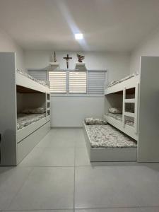 Cette chambre blanche comprend deux lits superposés et une croix. dans l'établissement Ap.Condomínio da Fe (1-6pessoas*, à Cachoeira Paulista