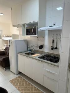 Il comprend une cuisine blanche équipée d'une cuisinière et d'un réfrigérateur. dans l'établissement Ap.Condomínio da Fe (1-6pessoas*, à Cachoeira Paulista