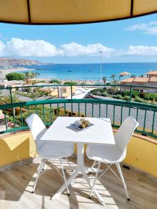 a white table and chairs on a balcony with the ocean at SOL & MAR Playa de las vistas Torres del Sol A504 in Arona