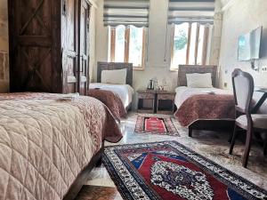 a bedroom with two beds and a chair and a rug at Lucky Cave Hotel Cappadocia in Göreme