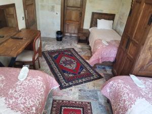 Cette chambre comprend 3 lits, une table et un tapis. dans l'établissement Lucky Cave Hotel Cappadocia, à Gorëme