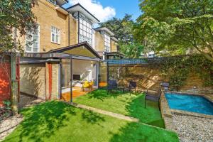 a backyard with a swimming pool and a house at 3 Bedroom Mews Home - Clapham Common - Free Private Parking - Sleeps 5 - Newly Refurbished - Sweetpea & Pillow Properties in London
