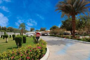 a stop sign in a park with flowers and palm trees at Le Meridien Medina in Al Madinah