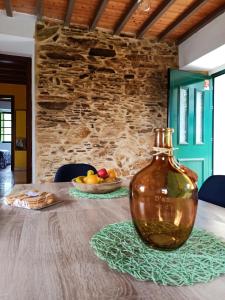 een glazen fles op een tafel met een fruitschaal bij A casa do Porto in Valdoviño