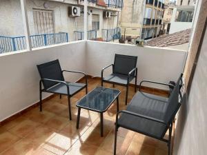 three chairs and a table on a balcony at BeniSol tu hogar en Benidorm in Benidorm