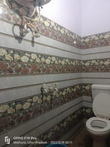 a bathroom with a toilet and rocks on the wall at Goroomgo Shree Anand Guest House Mathura in Mathura