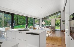 3 Bedroom Awesome Home In Silkeborg في سيلكبورج: مطبخ وغرفة طعام مع خزائن بيضاء ونوافذ كبيرة