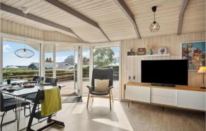 ein Wohnzimmer mit einem TV, einem Tisch und Stühlen in der Unterkunft Awesome Home In Bjert With Wifi in Binderup Strand