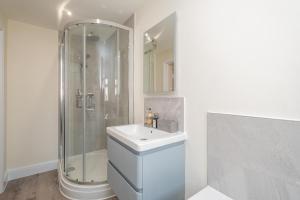 ein weißes Badezimmer mit Waschbecken und Dusche in der Unterkunft Avocet Cottage in Aldeburgh + 26 Fotos