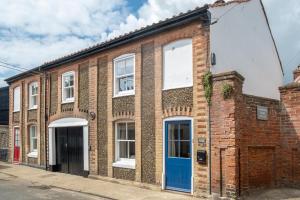 un bâtiment en briques avec une porte bleue dans une rue dans l'établissement Avocet Cottage, à Aldeburgh