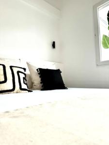 een wit bed met zwarte kussens en een raam bij LA GRAMA V, comodidad y excelente ubicación in Breña Alta