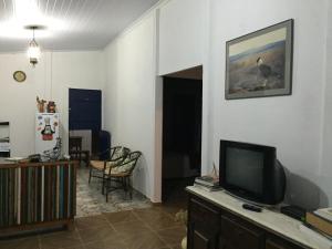 uma sala de estar com televisão numa cómoda em Casa do Alecrim em São Roque de Minas