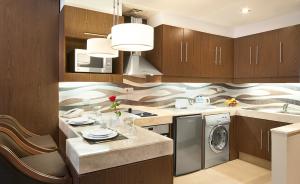 a kitchen with wooden cabinets and a washer and dryer at Oaks Liwa Executive Suites in Abu Dhabi +10 photos