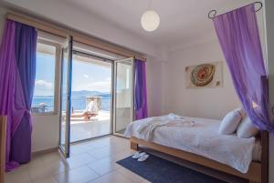 a bedroom with a bed with purple curtains and a balcony at Thea Hotel - Studios & Suites in Marmari