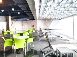 un restaurante con mesas blancas y sillas verdes en TopGenting SkyForestColdSty2R1B7Pax @GrdIonDelmn, en Genting Highlands