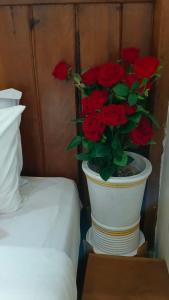 a vase with red roses in it next to a bed at Maison Model d'Angkor in Siem Reap