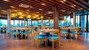 un restaurante con mesas, sillas azules y ventanas en Lovely Lady Villa Oceanami Resort, Vung Tau, en Long Hai