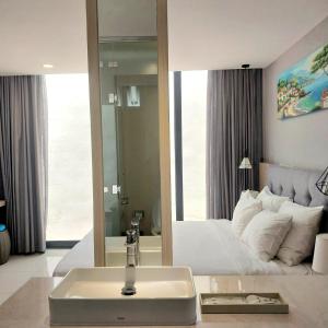 baño con lavabo y cama con espejo en Lovely Lady Villa Oceanami Resort, Vung Tau, en Long Hai