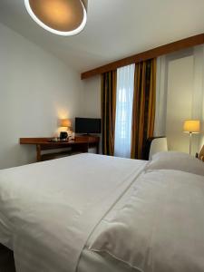 a bedroom with a large white bed and a desk at Hotel Admiral in Geneva