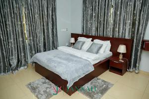 a bedroom with a bed and a window with curtains at JANNAH VILLAS - GHANA in Adentan