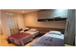 a room with two beds and a chair in it at Apartamento Estúdio 306 na ZN in Porto Alegre