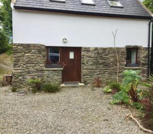 a stone house with a brown door and a window at Fernery Garden cottage, near Skibbereen in Drishanebeg
