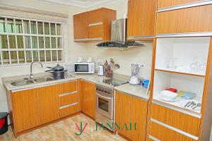 a kitchen with wooden cabinets and a sink and a microwave at JANNAH VILLAS - GHANA in Adentan