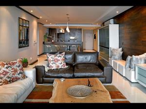 a living room with a leather couch and a table at The Crystal 203 Camps bay - back-up power in Cape Town