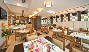 une salle à manger avec des tables et des chaises dans un restaurant dans l'établissement Oaks Liwa Executive Suites, à Abu Dhabi