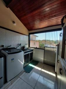 a kitchen with a washing machine and a window at Flats Tartaruga Búzios in Búzios