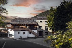 a white building with a roof on a street at Rousa little guesthouse Cosy in Rasun di Sopra