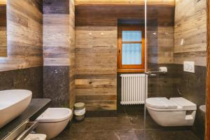 a bathroom with wooden walls and a toilet and a window at Agriturismo Ferdy in Lenna