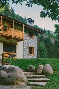 a house with a balcony and rocks in front of it at Agriturismo Ferdy in Lenna