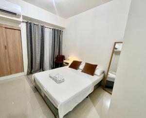 ein weißes Schlafzimmer mit Bett und Spiegel in der Unterkunft Condo Saga Davao City in Davao City + 23 Fotos