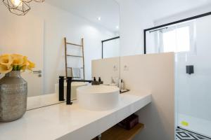 a white bathroom with a sink and a vase with flowers at MHouse lease Cascais Av 25 Abril in Cascais +25 photos