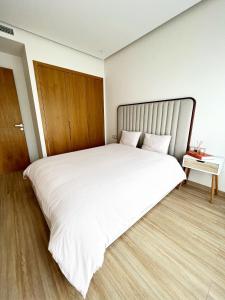 a bedroom with a large white bed with a wooden floor at Belle loge in Casablanca