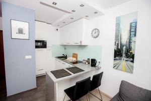 uma cozinha com armários brancos e um relógio na parede em Luxury Green Kabaty Apartament nr 6 em Varsóvia