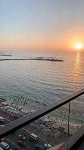 a view of a beach at sunset from a balcony at شقة فندقية فاخرة luxury apartment sea view in Alexandria