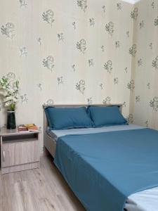sypialnia z niebieskim łóżkiem i ścianą z kwiatami w obiekcie 1-комнатная квартира в центре w mieście Kokczetaw
