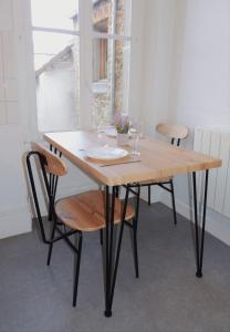 - une table en bois avec des chaises et des verres à vin dans l'établissement Appartement Cosy, à Poissy