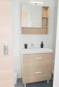 La salle de bains est pourvue d'un lavabo et d'un miroir. dans l'établissement Appartement Cosy, à Poissy