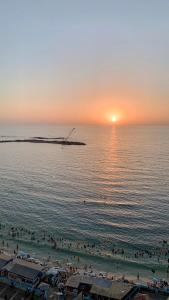 a group of people on a beach at sunset at شقة فندقية فاخرة luxury apartment sea view in Alexandria