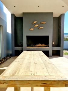 una mesa de madera en una sala de estar con chimenea en Henties Bay Haven Holiday Home, en Henties Bay