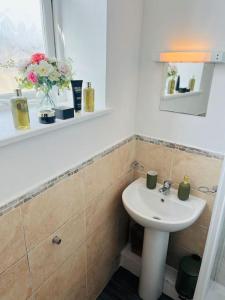 een badkamer met een wastafel en een vaas met bloemen bij Studio flat in Shipley Central in Shipley